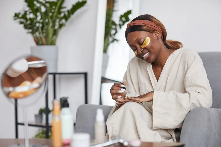 A woman sitting on the couch and doing her nails. 